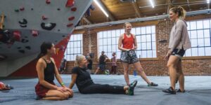 Indoor climbing wall with a climber mid-route, focusing on the sport and movement inside a climbing gym